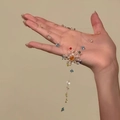 Gros plan d'un collier pendentif floral coloré fait main sur un fil de nylon transparent - Blanc-Bleu-Vert-Fleur
