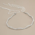 Détail d'un serre-tête argenté ondulé avec d'élégants pompons en perles de cristal - Blanc