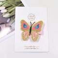 Close-up of a glittery butterfly hair clip with colorful polka dots on a white display card - Green Pink Butterfly