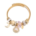 Dettaglio del bracciale a perline dorate con ciondoli a luna, sole e cristallo rosa - Bianco