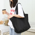 Minimalist black vintage washed canvas tote bag shown as a shoulder bag on model - Black