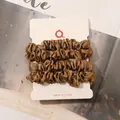 Detail of 4-piece bronze satin scrunchies set with silky texture on display card - Gold