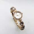 Detailed view of luxury golden quartz watch with sparkling rhinestones and floral bracelet - White
