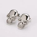 Detalle macro de pendientes de calavera plateada con diamantes de imitación claros - Color Acero