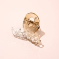 Macro shot of a transparent acetate mini hair claw clip with a durable metal spring - Cross Gold