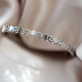 Vue macro d'un bracelet alvéolé en argent avec zircons sur un fond en soie douce - Bracelet Nid d'Abeille Argent