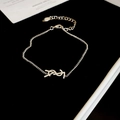 Macro shot of silver letter pendant necklace on black velvet with lobster clasp detail - Bracelet - Silver