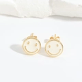 Detailed close-up of golden smiley face earrings with white enamel on a white stone background - White