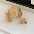 Dettaglio di set bracciale e anello a fiore dorato con trame di petali incise - Set Bracciale e Anello con Fiori Dorati