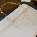 Dettaglio della collana di perle a più strati con catene dorate su espositore beige - Collana-Oro-Perla