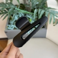Dettaglio della grande pinza per capelli nera opaca con design traforato tenuta in mano - Nero opaco