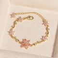 Luxuriöses Goldarmband mit rosa Kirschblütenkristallen und Zirkonia auf beigem Samt - Blume Rosa Zirkon Gold