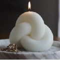 Minimalist white knot-shaped soy wax candle burning on a marble tray - Knot Candle