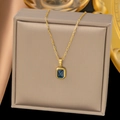Elegant gold necklace with rectangular blue gemstone pendant on a beige jewelry box - Blue Rhinestone Pendant (H640)