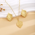 Elegant gold leaf shape necklace and earrings set on a minimalist textured background - Gold Cross Leaf Style