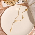 Elegant gold Y-shaped necklace with LOVE letters on a white ceramic plate - Alphabet / Gold
