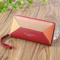 Detail of color-block patchwork wallet with wristlet strap on a wooden surface - Dark Red