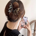 Detail of a metallic bat-shaped hair claw clip worn on a half-up hairstyle by a model - Gunmetal