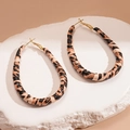 Dettaglio degli orecchini a cerchio in pelle leopardata su una superficie in pietra bianca - Orecchini a Cerchio Goccia Caffè