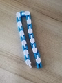 Blue and white wacky tracks fidget toy in a U-shape on a wooden surface - White and Blue