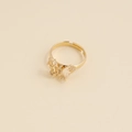 Dettaglio dell'anello a farfalla dorato con pietre in zirconia su sfondo beige neutro - Aperto Regolabile / Bianco