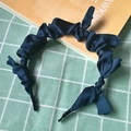 Close-up of a dark blue pleated wavy headband with shiny satin finish and bow detail - Dark Blue (Cloth Pleated)
