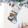 Detail eines grün-beige karierten Nikolausstrumpfs mit Plüschbär und Holzschild-Deko - Bär