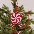 Brown gingerbread man Christmas ornament with red and white candy detail on green branches - Gingerbread Man with Swirl Candy Style L