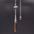 Macro shot of tiger eye stone crystal pendulum with silver heart wing metal detail - Tiger's Eye