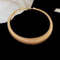 Detailed close-up of a golden metal choker necklace with intricate spiral thread texture - Gold