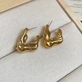 Detailed view of gold irregular lava-style earrings resting on a beige linen jewelry box - Gold V-Shape With Steel Pin