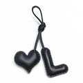 Detail of handmade black leather bag charm featuring a heart and letter L with fine stitching - Black L with Black Heart