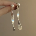 Dettaglio di orecchini di perle argentate con pendenti a nastro metallico ondulato - Stile Torsione Perla Argento Opaco (HE28008)