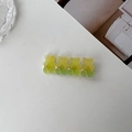 Flat lay of a cute gummy bear hair clip in gradient yellow-green resin on a white desk - Yellow