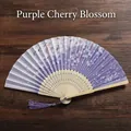 Close-up of a purple folding fan with cherry blossom patterns and a matching silk tassel - Purple Sakura