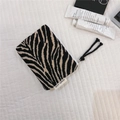 Detail of zebra-patterned knit pouch featuring a black tassel zipper and side logo tag - Chenille Black