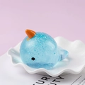 Sparkly blue narwhal squishy toy with glitter finish for stress relief on a white plate - Glitter Narwhal / Blue