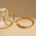 Detailansicht großer goldener Creolen mit schwarzem CELINN-Schriftzug und hochglänzender Politur - Kreis-Stil / Gold