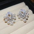 Macro shot of vintage pearl earrings with zircon stones on a beige display box - Silver