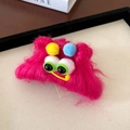 Close-up of pink plush monster hair claw clip with colorful pompoms and large plastic eyes - Hair Claw