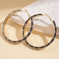 Dettaglio di grandi orecchini a cerchio dorati avvolti in tessuto tweed bianco e nero - Perno in Argento - Pied de Poule Bianco e Nero