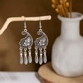 Detailed shot of bohemian silver drop earrings with floral engraving on wooden stand - E2874-3/Flower Teardrop Tassel