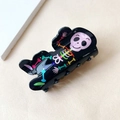 Detail of a black plastic hair claw clip with colorful cartoon skull patterns on top - Skull