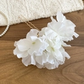 Detailed view of white fabric floral hair pin with elegant gold U-shaped metal fork - White