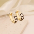 Macro detail of gold-plated evil eye hoop earrings with enamel drip oil finish - Black