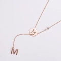 Collana a Y in oro rosa con pendenti a lettera M e zircone su sfondo bianco - Oro rosa