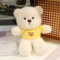 Cute white plush teddy bear wearing a bright yellow hoodie seated on a desk - 30cm Yellow Hoodie Bear
