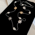 Lange ketting met bloem- en schelphangers in goud en zilver op zwart fluweel - Goud en Zilveren Bloemen schelp