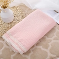 Close-up detail of pink double-layer muslin baby blanket with delicate white lace trim. - Pink