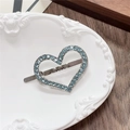 Close-up of heart-shaped silver clip with blue rhinestones on a ceramic tray - Heart / Green